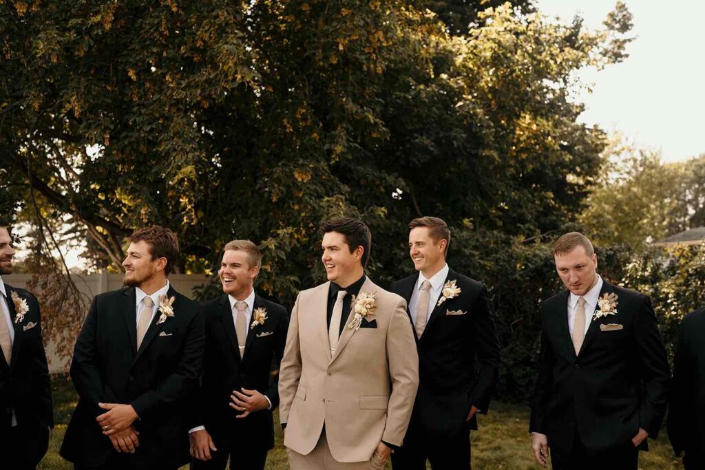 Bride and groom embracing in front of a macrame-decorated ceremony arch at The Pines, surrounded by evergreen trees.