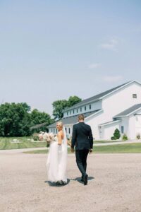 Bride and groom holding hands outside The Pines, with their wedding venue in the background.