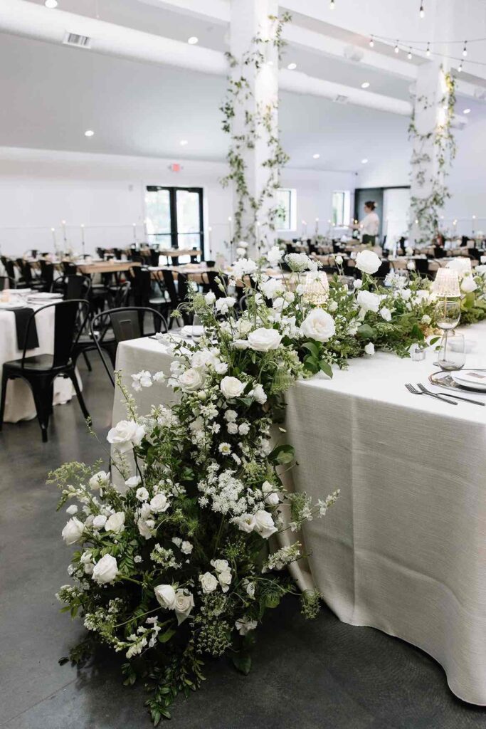Close-up of a stunning white floral arrangement at the head table of a wedding reception at The Pines, highlighting luxury wedding decor.