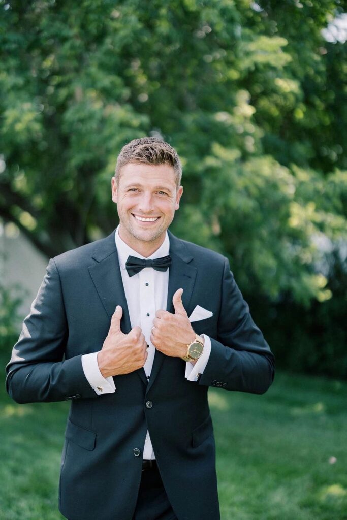 Portrait of the groom standing outdoors at The Pines wedding venue, looking dapper in his tuxedo.