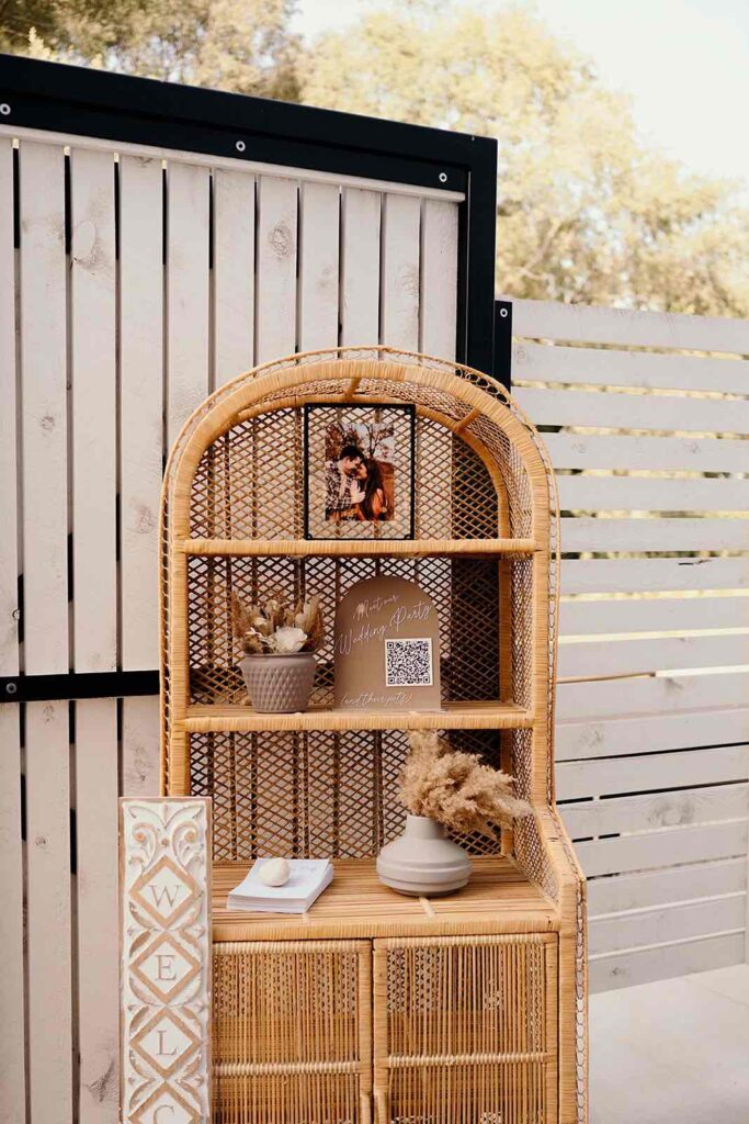 A close-up of a groom in a tan suit adjusting his tie, wearing a dried floral boutonniere with natural, bohemian tones.