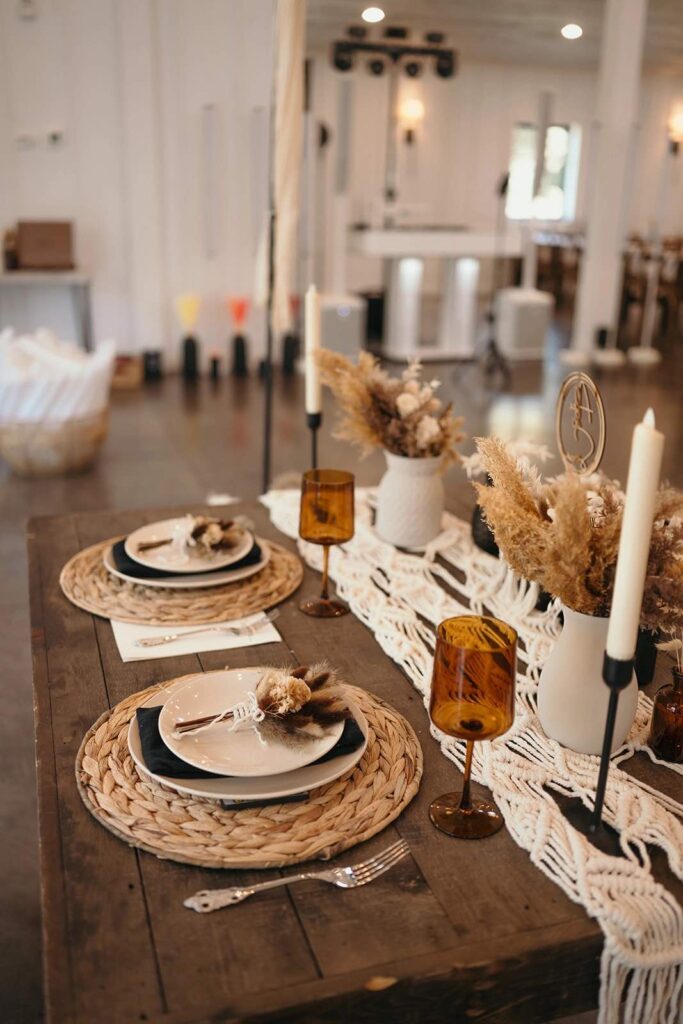 Boho tablescape with rattan place settings, amber-colored glasses, and boho florals on the sweetheart table for the bride and groom.