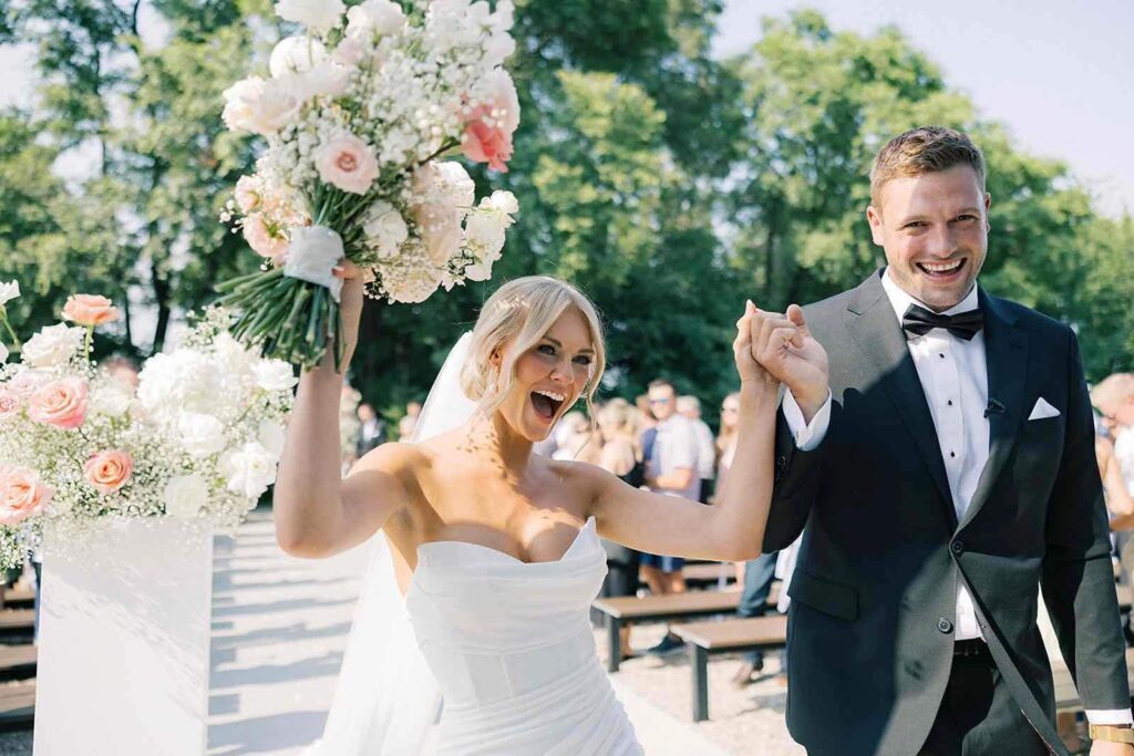 Bride and groom sharing a romantic moment after their ceremony at The Pines, with a floral bouquet.