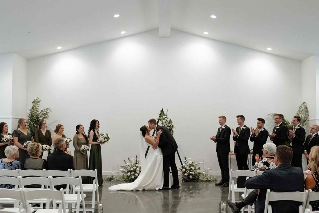 Bride and groom sharing their first kiss during the wedding ceremony at The Pines.