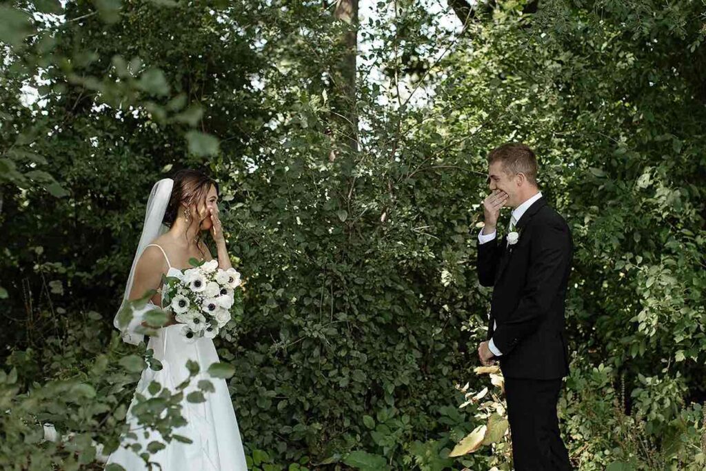 Emotional first look between the bride and groom, surrounded by lush greenery in an outdoor woodland setting.