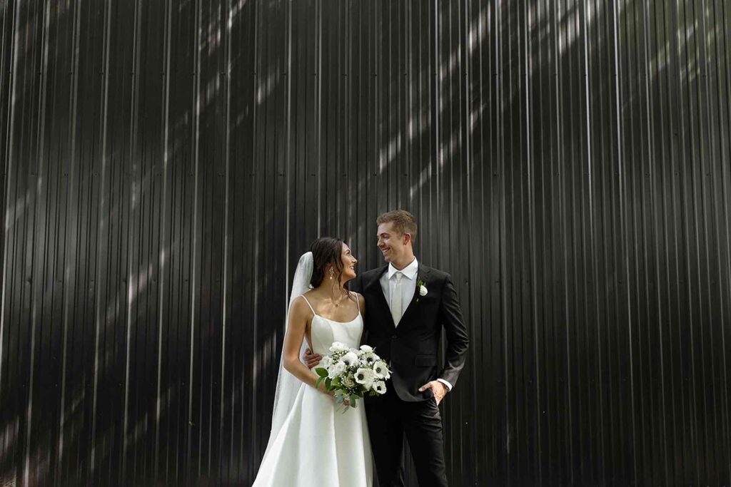 An elegant portrait of Bride and Groom against a dramatic metal wall, capturing their timeless love.