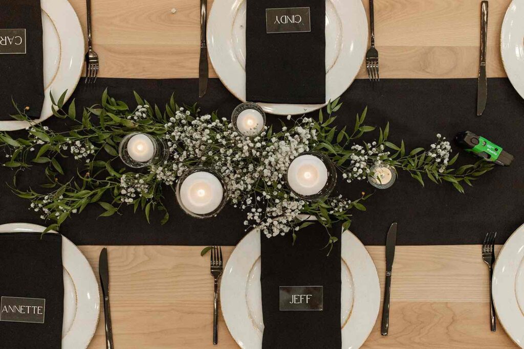 Elegant tablescape at The Pines featuring greenery, floating candles, and personalized black napkins