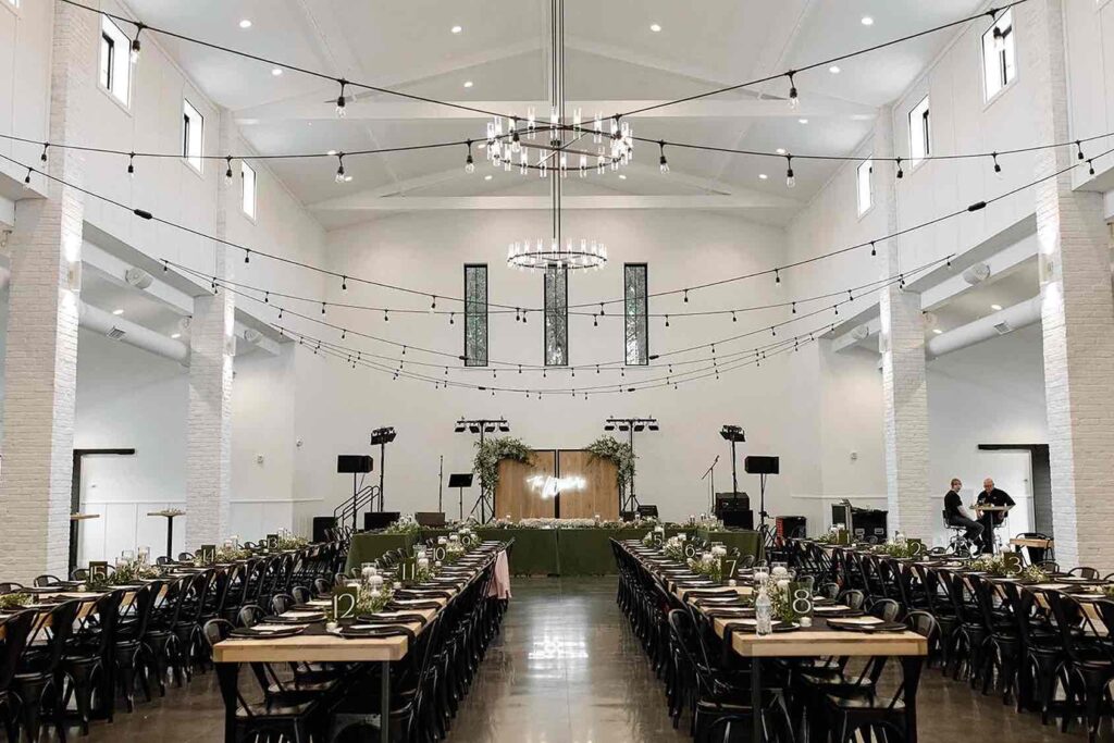 Grand reception hall at The Pines with string lights and modern chandeliers creating a cozy ambiance