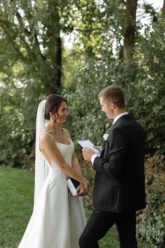 Couple exchanging heartfelt vows in a serene outdoor setting with a natural green backdrop.