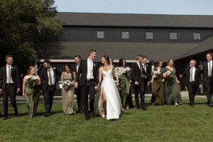 Couple walking with their wedding party dressed in black and green at The Pines