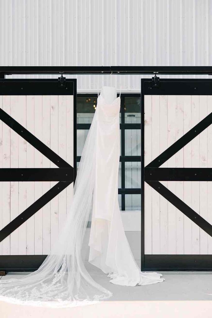 Bridal gown hanging elegantly from the barn doors at The Pines, ready for the big day.