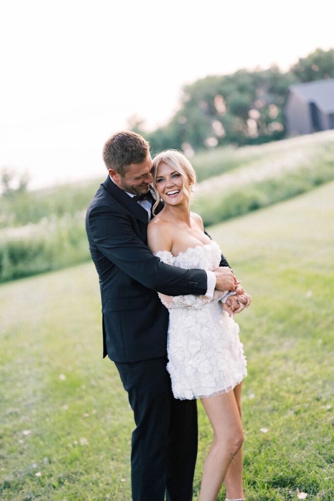 Bride and groom embracing in a lush outdoor setting, with golden sunset light creating a dreamy, romantic wedding portrait at The Pines.
