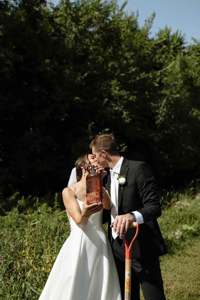 Couple celebrating a whiskey-burial tradition, symbolizing good weather on their wedding day.
