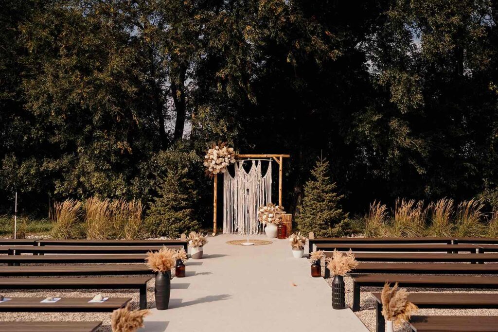 Outdoor boho ceremony space during a September wedding at The Pines against a greenery landscape.