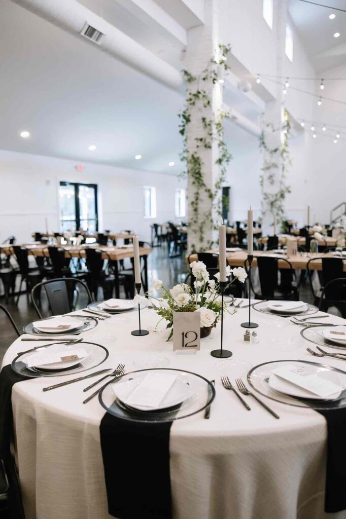 Beautiful wedding reception table decor at The Pines featuring candles, floral centerpieces, and classic black and white design.