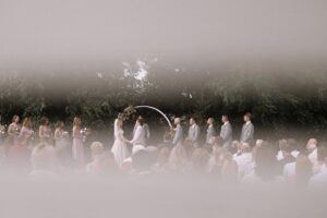 Outdoor wedding ceremony at The Pines venue with floral arch, bridal party, and guests gathered for a beautiful moment in nature.