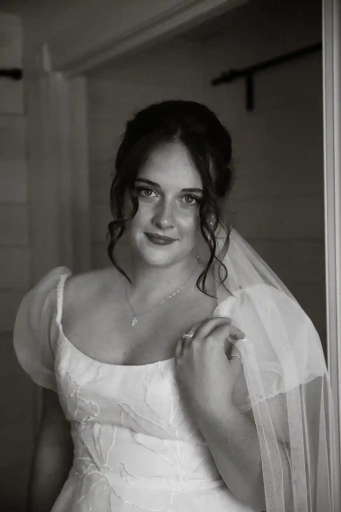 Bride in a puff-sleeve wedding gown smiles softly while getting ready in the bridal suite