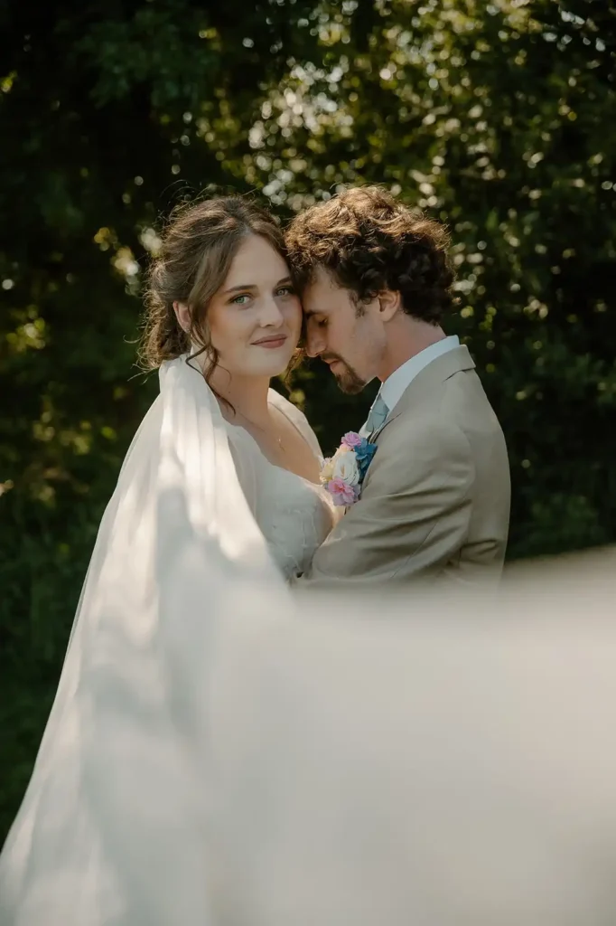 Romantic close-up wedding portrait of bride and groom wrapped in a flowing veil