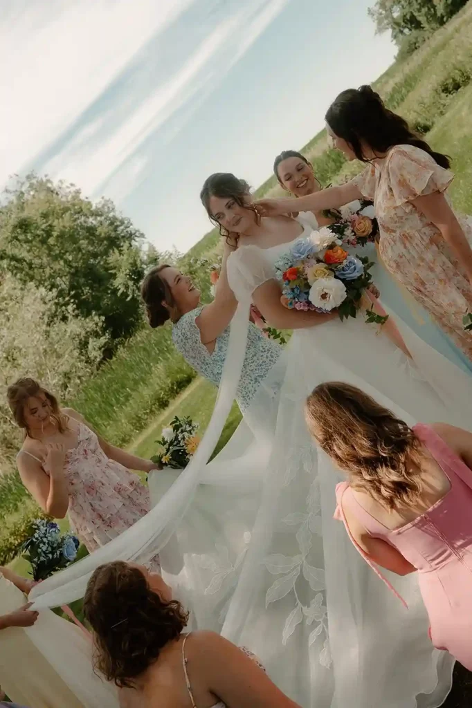 Bridesmaids help the bride adjust her flowing veil and floral bouquet before the ceremony at The Pines North Dakota wedding venue