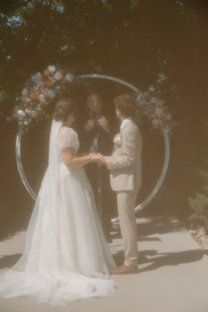 hazy edited photo of outdoor ceremony in front of white circle arch